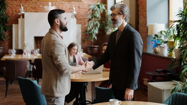 two people shaking hand in a coffee shop